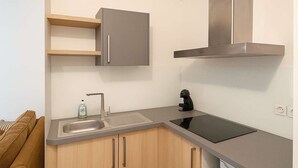Cocina compacta con lavamanos, estufa y armarios.