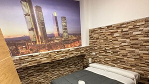 A hotel room with a bed, a cityscape mural on the wall, and a stone-patterned headboard.