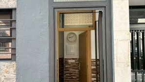 A doorway leading to a room with a clock, a textured wall, and a door with a metal handle.