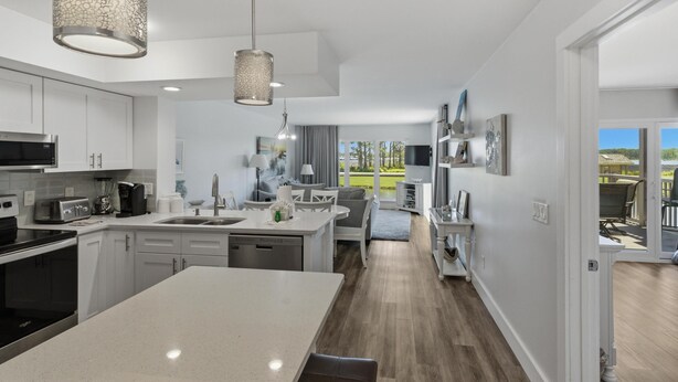 Una cocina moderna con armarios blancos, una isla central e iluminación colgante.