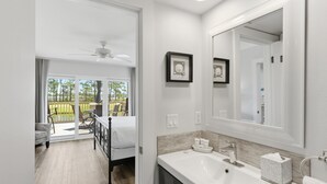 Un baño moderno con un espejo grande, un lavamanos y un inodoro. Cuenta con un balcón con una silla y una mesa.