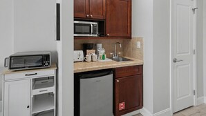 A compact kitchen with a microwave, toaster, dishwasher, and wooden cabinets. - Studio condo on 7th Floor at Luau in Sandestin Golf & Beach Resort (Miramar Beach)