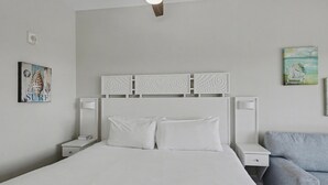 A neatly arranged bedroom with a bed, bedside tables, a ceiling fan, and artwork on the walls. - Studio condo on 7th Floor at Luau in Sandestin Golf & Beach Resort (Miramar Beach)