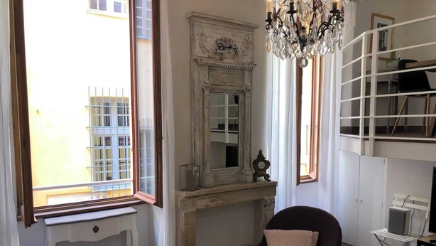 Um quarto com lareira, um candelabro, um sofá e uma poltrona.