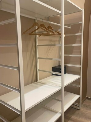 A white storage unit with multiple shelves and a hanging rack. - Mado Suite 112 Elegance, comfort and smart access (Bari)