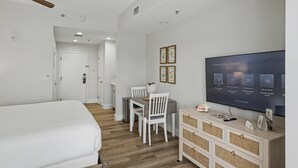 Une chambre d’hôtel comprenant un lit, un bureau avec une chaise, une télévision et un petit meuble de rangement.