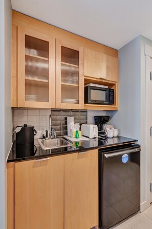 A compact kitchen with wooden cabinets, a microwave, a coffee maker, a toaster, and a refrigerator. - Studio condo at Bahia in Sandestin Golf & Beach Resort (Miramar Beach)