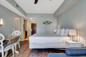 A hotel room with a bed, bedside table, lamp, and a dining area with chairs. - Studio condo at Bahia in Sandestin Golf & Beach Resort (Miramar Beach)
