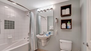 Une salle de bain équipée d’une baignoire, de toilettes, d’un lavabo et d’un rideau de douche.