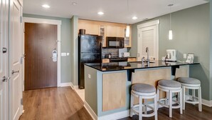 A modern kitchen with a central island, bar stools, and a microwave. - 2BR Bahia Suite at Golf & Beach Resort (Miramar Beach)