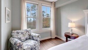 A hotel room with a bed, a chair, a nightstand with a lamp, and a window with curtains. - 2BR Bahia Suite at Golf & Beach Resort (Miramar Beach)