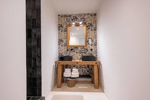 A bathroom with a wooden vanity, a mirror, and a patterned wall. - Domaine Mas Lafleur - Mas Provençal for 12 people - Swimming pool & large garden (Châteaurenard)
