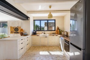 Une cuisine moderne dotée d’un grand réfrigérateur, de meubles en bois, d’une fenêtre offrant une belle vue et d’un luminaire suspendu.