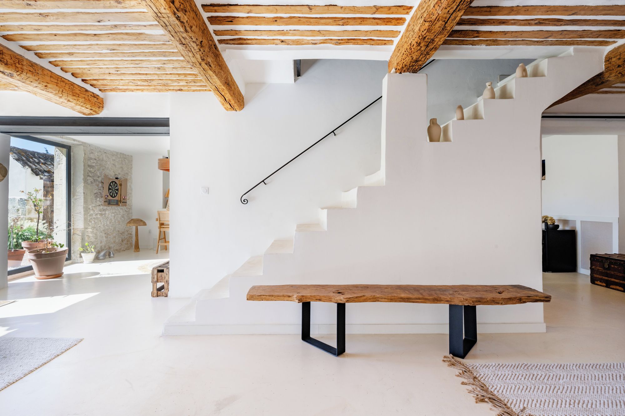 A modern interior with a wooden bench, a staircase, and a view of the outdoors.