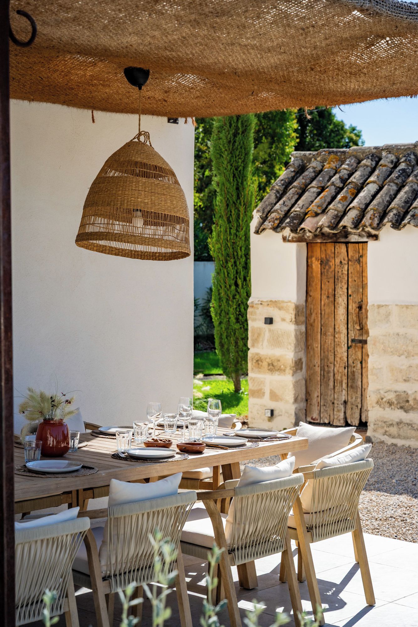 Un espace extérieur aménagé pour les repas, avec une table ronde pour quatre personnes, entourée de chaises en osier.
