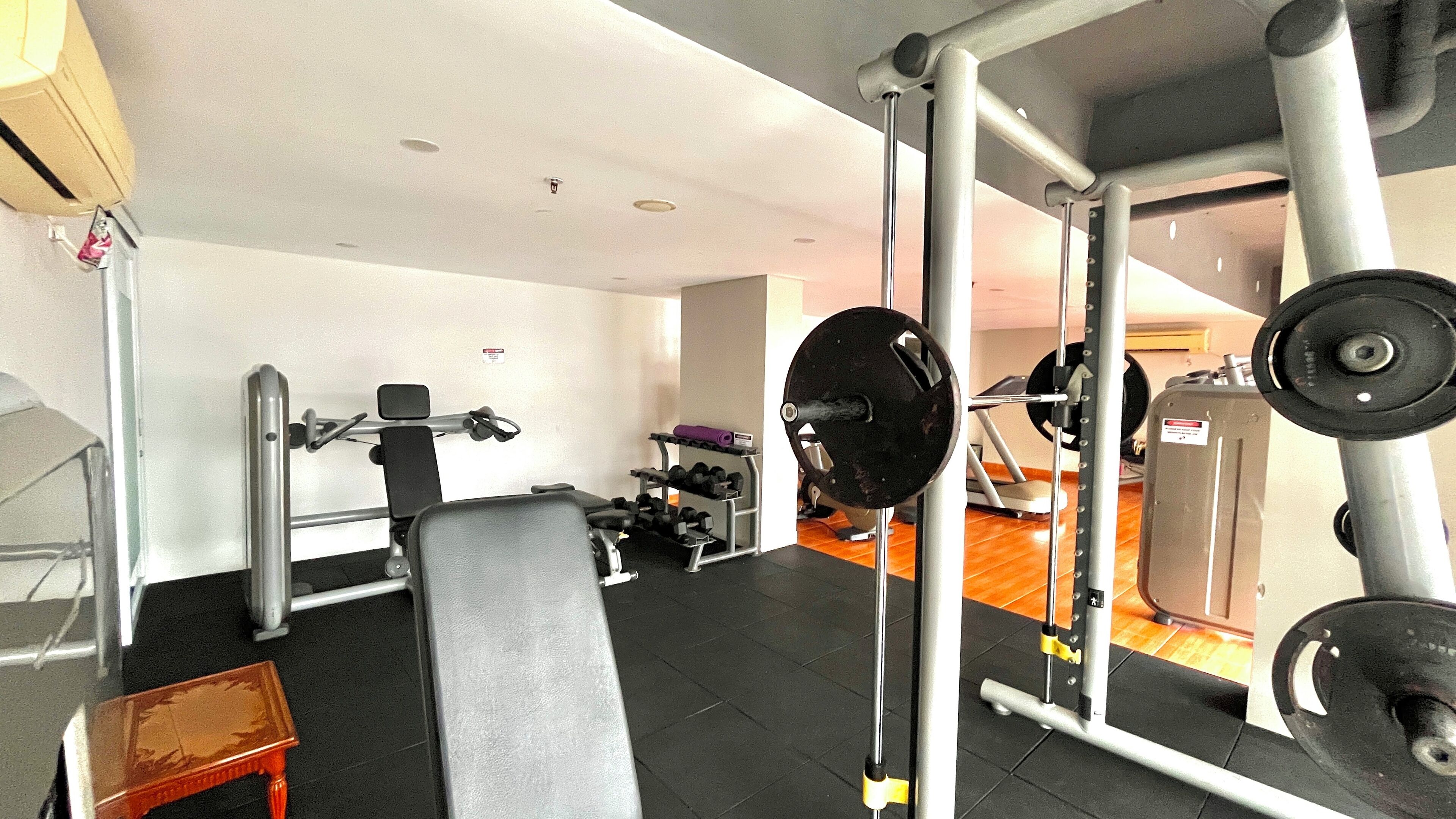 A gym with various exercise equipment, including a bench, squat rack, and weight bench.