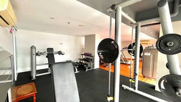 A gym with various exercise equipment, including a bench, squat rack, and weight bench.