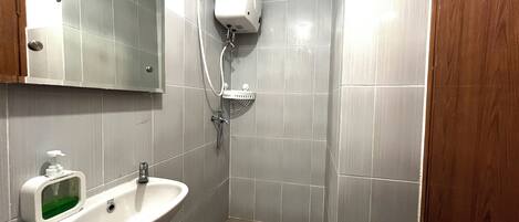 A bathroom with a sink, mirror, and shower.