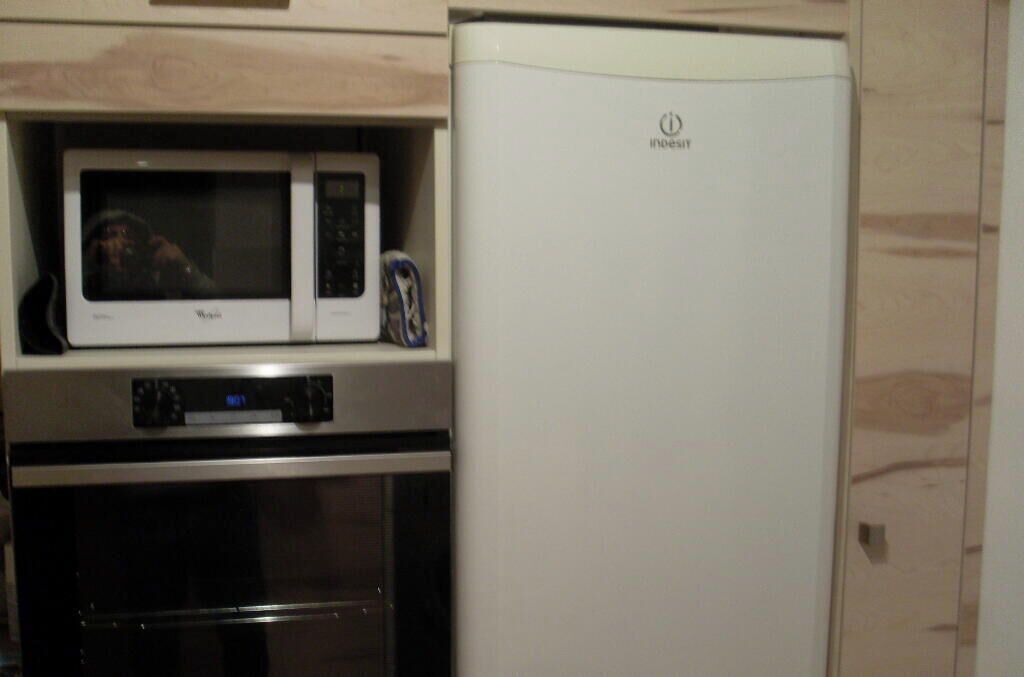 A kitchen with a microwave, oven, and a white refrigerator.