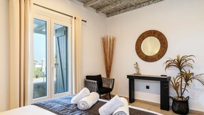 Una camera d'albergo con un letto, una sedia, un tavolino, uno specchio e una pianta in vaso.