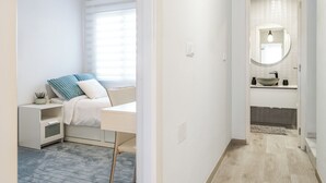 A modern bedroom with a bed, bedside table, and a window with blinds. - Sun-Kissed 3BR Townhouse by Pool, Near Carabassi Beach (Gran Alacant)