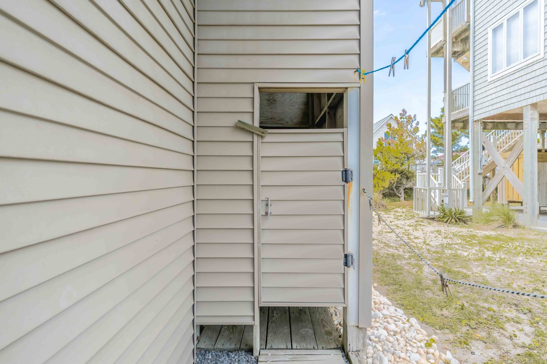 A beige exterior wall with a small door and a wooden deck area.