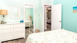 A bedroom with a bed, dresser, and a door leading to another room. - 2nd Wind - 2nd Row 3 BR Home - 2nd Floor Observation Deck (Surf City)
