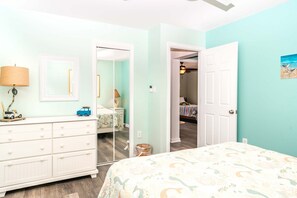 Ein Schlafzimmer mit Bett, Schminktisch und einer Tür zu einem anderen Raum.