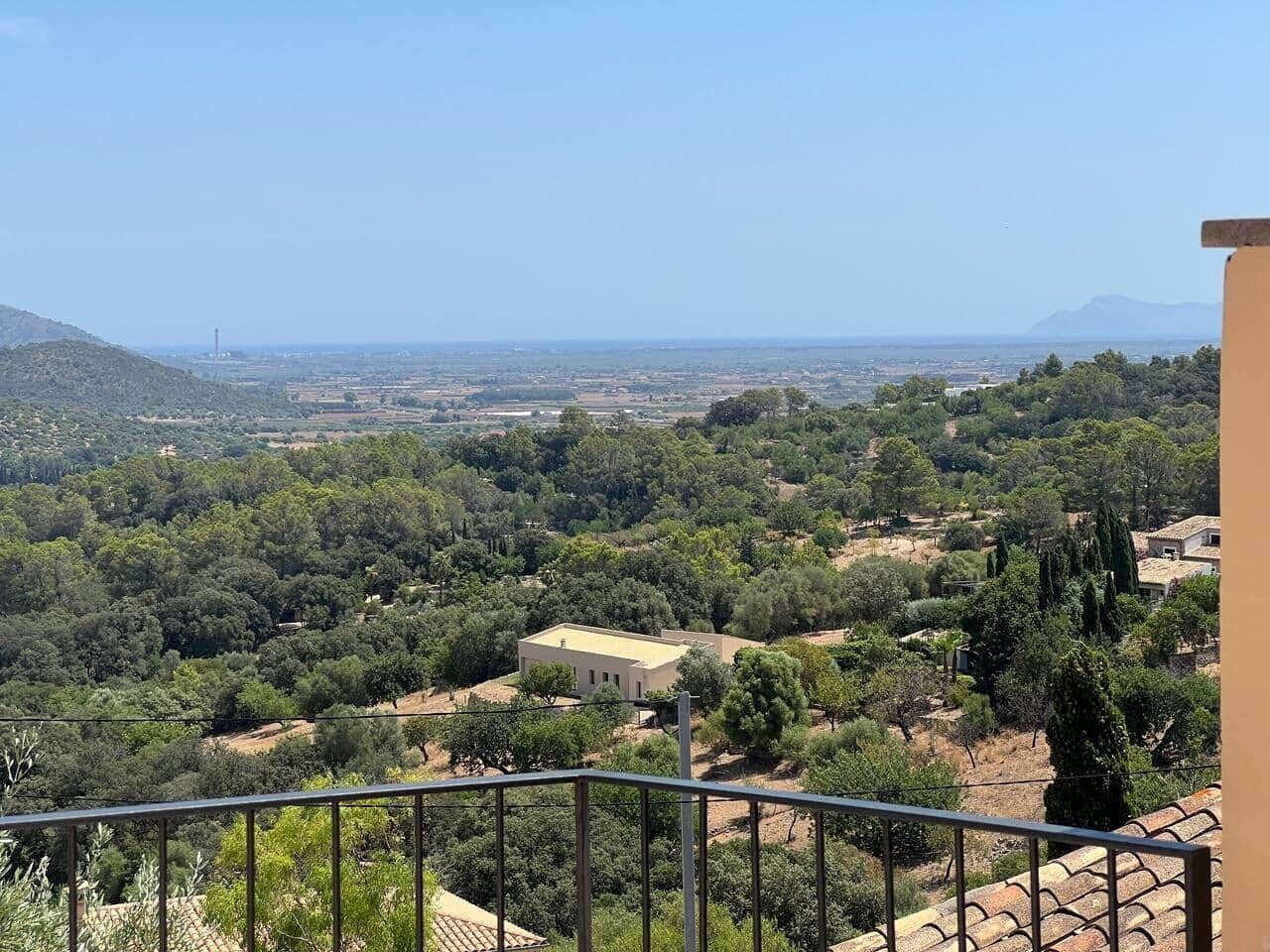 Ein Balkon mit Blick auf eine ländliche Landschaft, Bäume und ein weiter abgelegenes Gebäude.