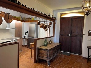 Een keuken met een houten plank waarop pannen, een magnetron en een koelkast staan.