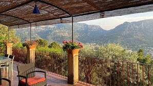 An outdoor terrace with a view of mountains, a table with chairs, and potted plants. - Soller Sunset Escape | Private Pool and Sea Views (Sóller)