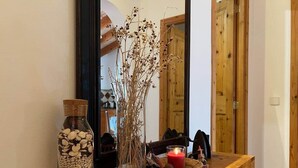 A wooden console table with a glass bottle of stones, a vase with dried branches, and a lit candle. - Soller Sunset Escape | Private Pool and Sea Views (Sóller)