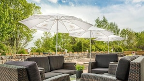 An outdoor seating area with wicker furniture and white umbrellas. - Kaiserhof Feldberg by Belvilla Resorts (Feldberger Seenlandschaft)