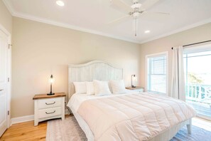 Un dormitorio con cama, mesitas de noche, ventilador de techo y una ventana con persianas.
