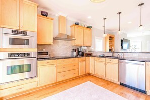 Una cocina moderna con electrodomésticos de acero inoxidable, armarios de madera y encimera de granito.
