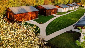 A row of rustic barns with metal roofs, surrounded by well-maintained lawns and trees. - Vlaštovčí recreation area (Radvanec)