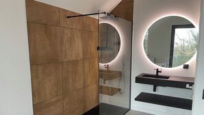 A modern bathroom with a glass shower enclosure, a round mirror with under-cabinet lighting, and a black countertop sink. - Near ARKEA ARENA for this room with an incredible view (Bouliac)