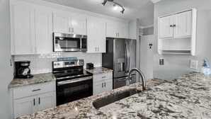 A modern kitchen with white cabinets, stainless steel appliances, and a granite countertop. - Ocean Dunes Villas (Myrtle Beach)