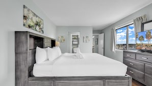 A modern hotel room with a large bed, grey wardrobe, and a TV on the right. - Ocean Dunes Villas (Myrtle Beach)