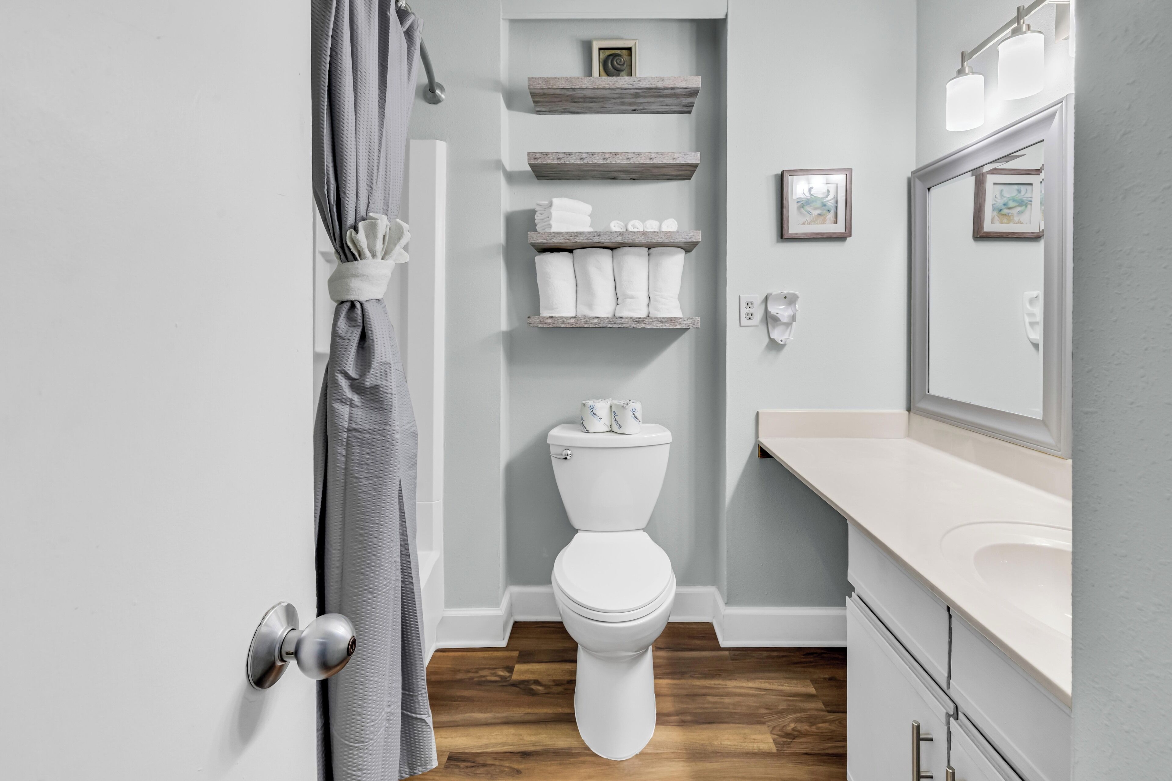 Een badkamer met toilet, houten planken, een spiegel en een douchegordijn.