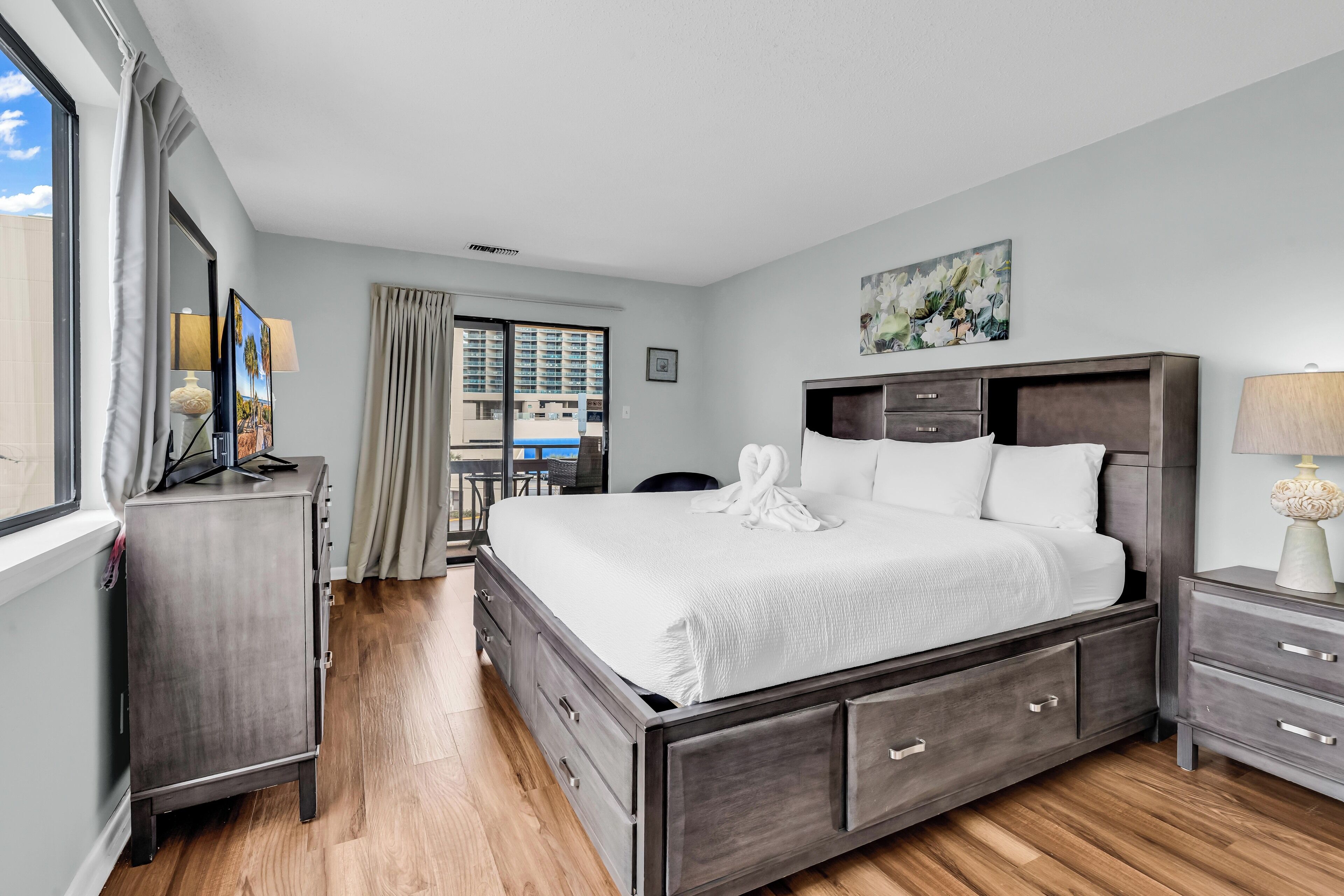 Ein Hotelzimmer mit einem großen Bett, einem Schminktisch, einem Schreibtisch und einem Fenster mit Vorhängen.