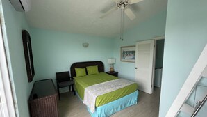 Un dormitorio con cama, mesita de noche, lámpara y ventilador de techo.