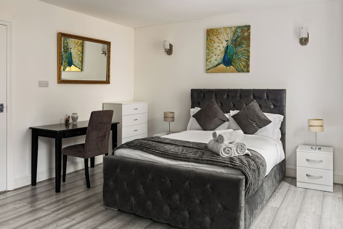 Una camera da letto con un letto, una scrivania, una sedia e opere d'arte alle pareti.