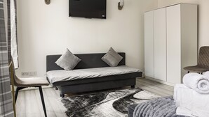 A modern bedroom with a bed, a TV mounted on the wall, a wardrobe, and a chair. - Crawford place studio apartments (London)