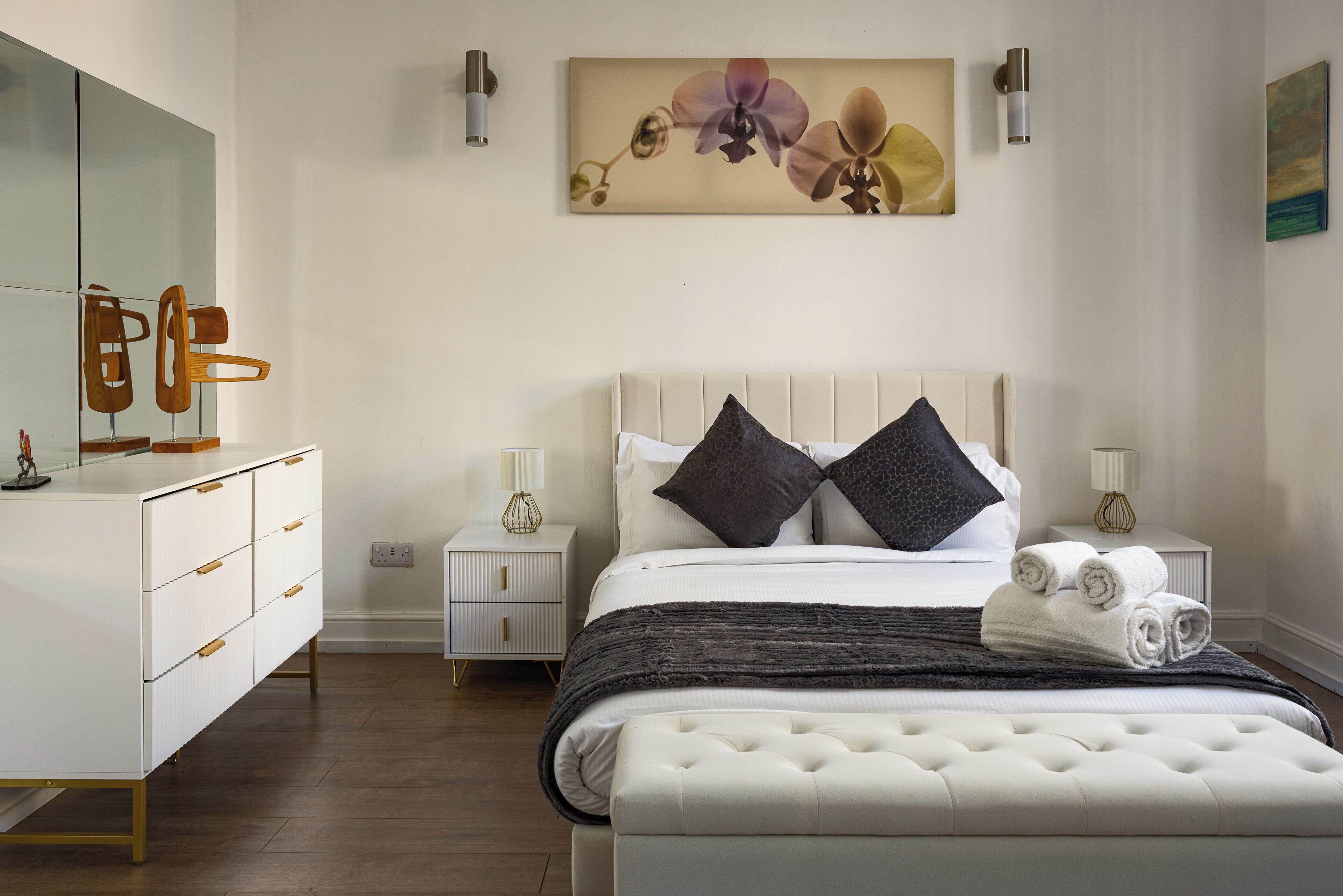 Ein modernes Schlafzimmer mit einem großen Bett, Nachttischen, einem Schminktisch und einem Spiegel.