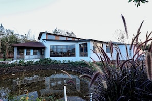 Una casa moderna con ventanas amplias, un sendero de piedra y un estanque.