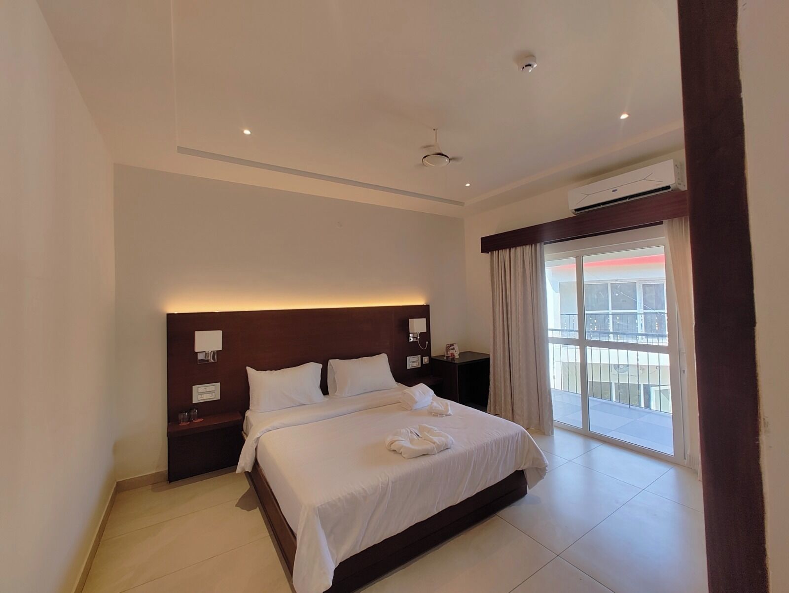 Una habitación de hotel con una cama grande, una mesita de noche y un equipo de aire acondicionado.