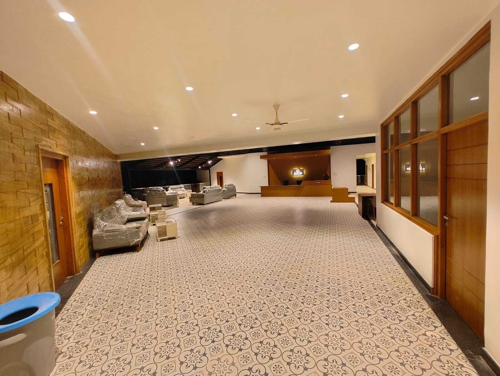 A spacious hotel lobby with a patterned carpet, a reception desk, and a large seating area.