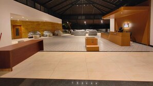 Een ruime lobby met een hoge plafond, een receptiebalie, een zithoek en uitzicht op de omgeving.