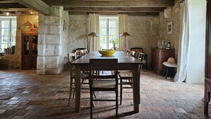 Un comedor rústico con una gran mesa de madera, sillas y un cuenco de fruta.